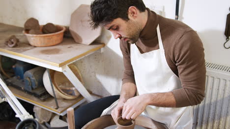 Un-Joven-Con-Delantal-Trabajando-En-Un-Torno-De-Alfarería-En-Un-Estudio-De-Cerámica.