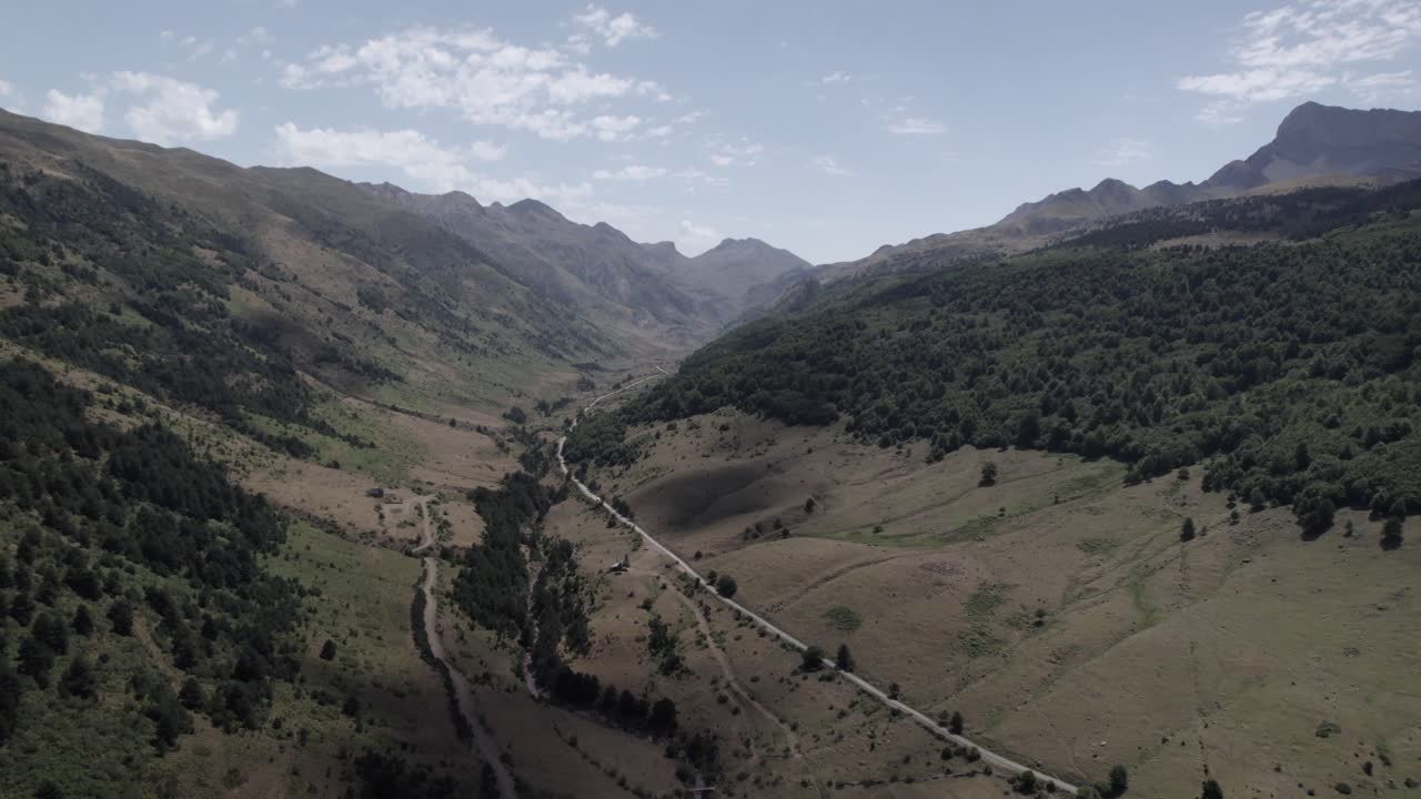 4K low-altitude frontal drone shot advancing over the trail to Ibón de Acherito in the Western Valleys Natural Park, Aragonese Pyrenees, Spain. A stunning cinematic view of the rugged landscape.