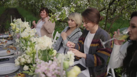 Gartenparty-Im-Frühling.-Menschen-Essen-In-Der-Blühenden-Obstgartengastronomie-Zu-Mittag