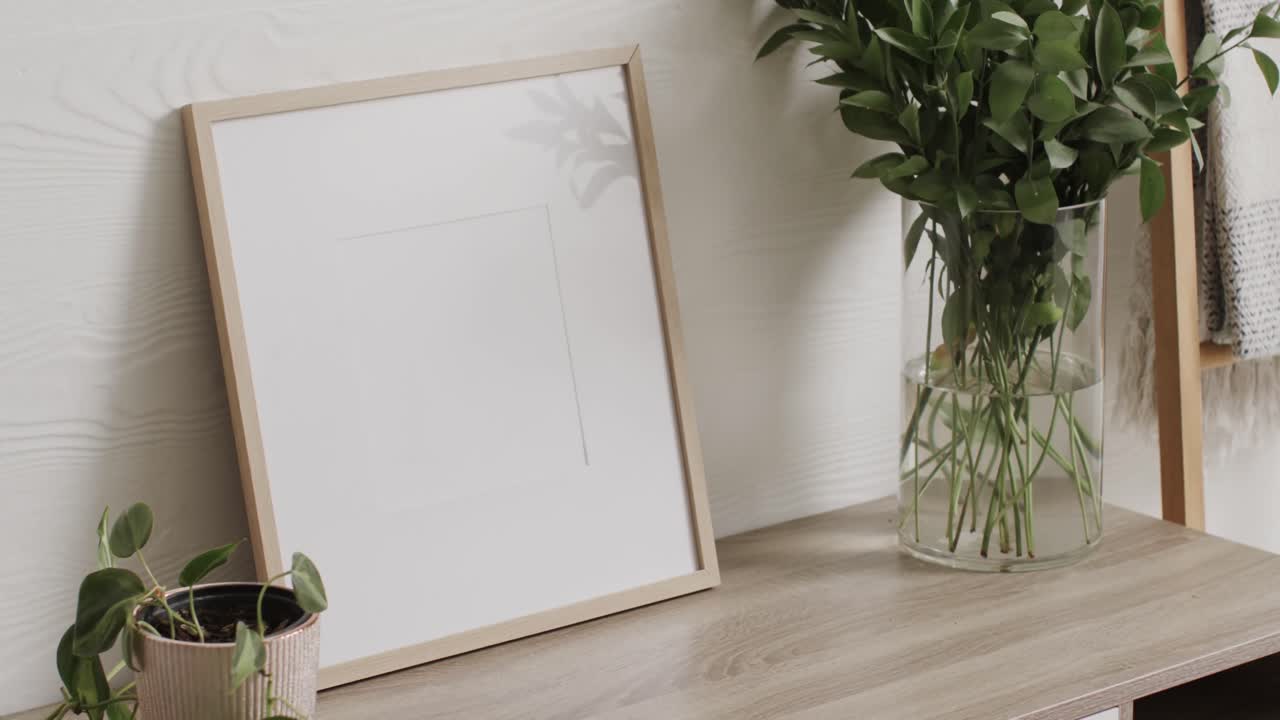 marco de madera con espacio de copia en fondo blanco con plantas en el escritorio contra la pared blanca