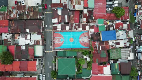 top-down aerial establishing shot of urban basketball court in third-world asian country with dilapidated rooftops