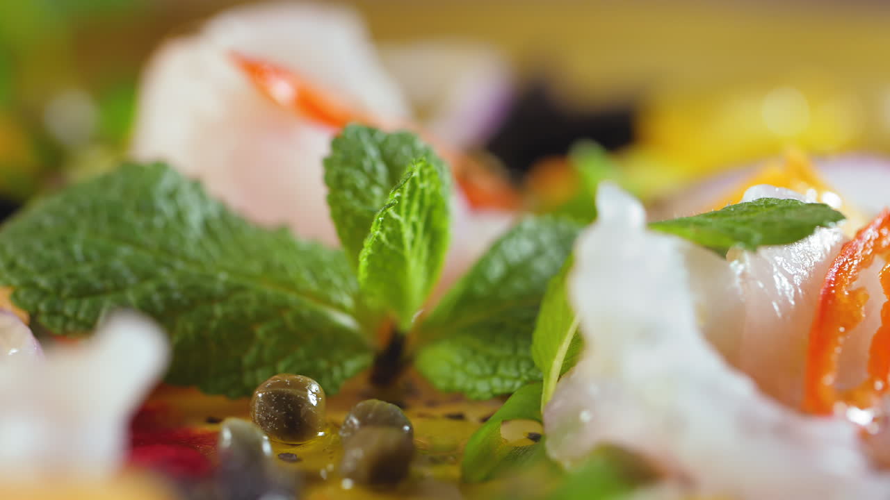세비치 요리의 극단적 인 클로즈업, 요리사가 민트 잎을 놓고, 카퍼,  ⁇  물고기, 고추, 토마토 및 올리브 오일 - 다채롭고 건강한 스페인-아메리카 요리