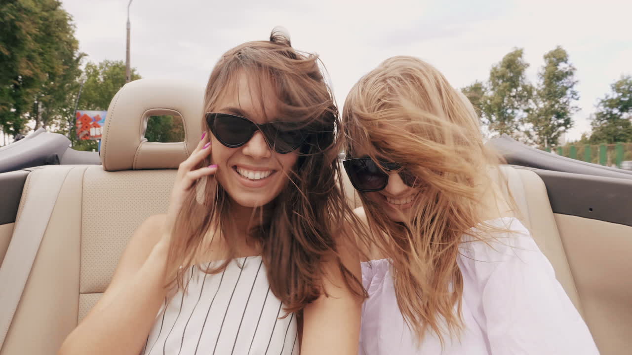 두 명의 여성이 컨버터블 차에서 재미를 느끼고 있습니다.