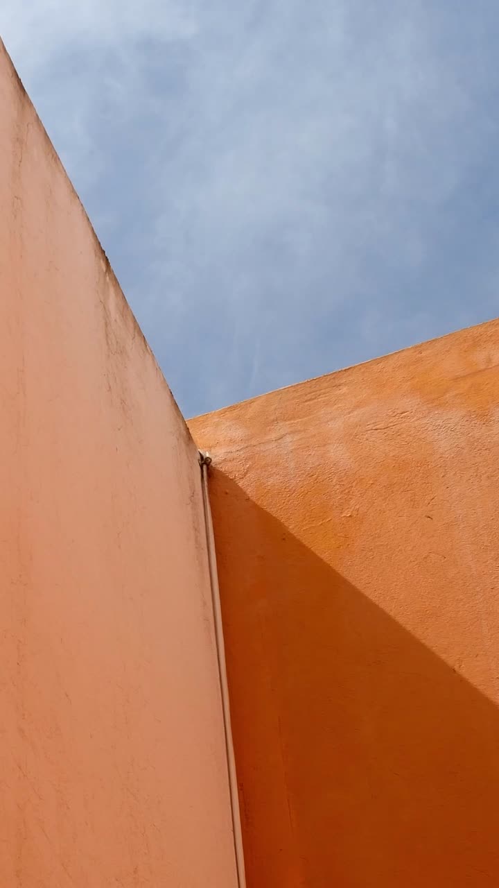 Low-angle view of a partially cloudy sky and colorful walls describing a geometric pattern