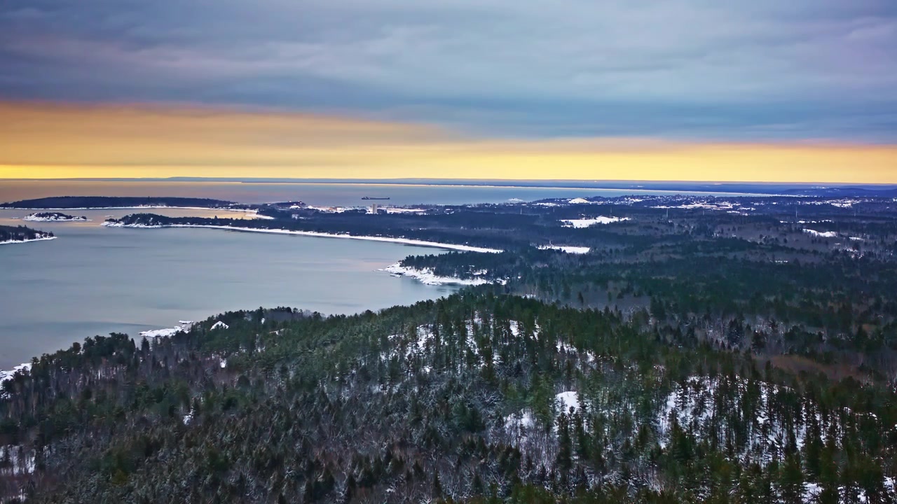 Laaja ilmakuva lumisista metsistä ja jäätyneestä maastosta Pohjois-Michiganissa.