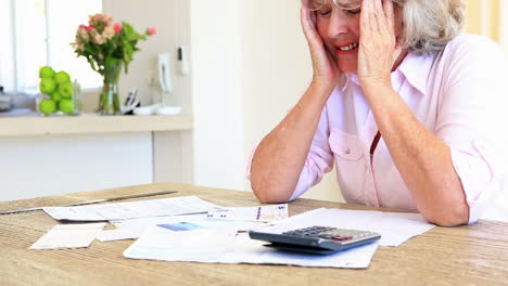 Senior-woman-sitting-at-table-paying-her-bills