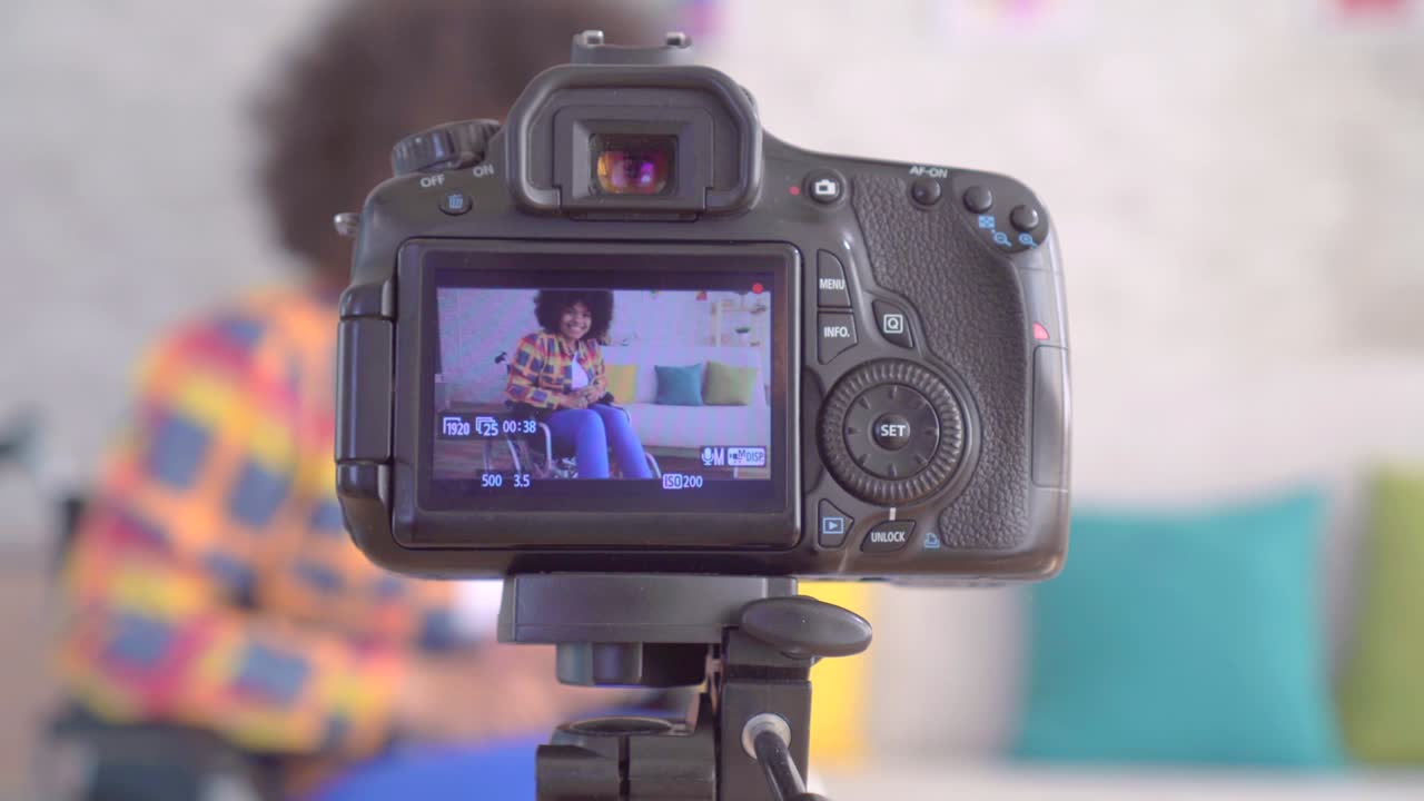 joven bloguera africana discapacitada en silla de ruedas con un peinado afro la vista a través de la pantalla de la cámara