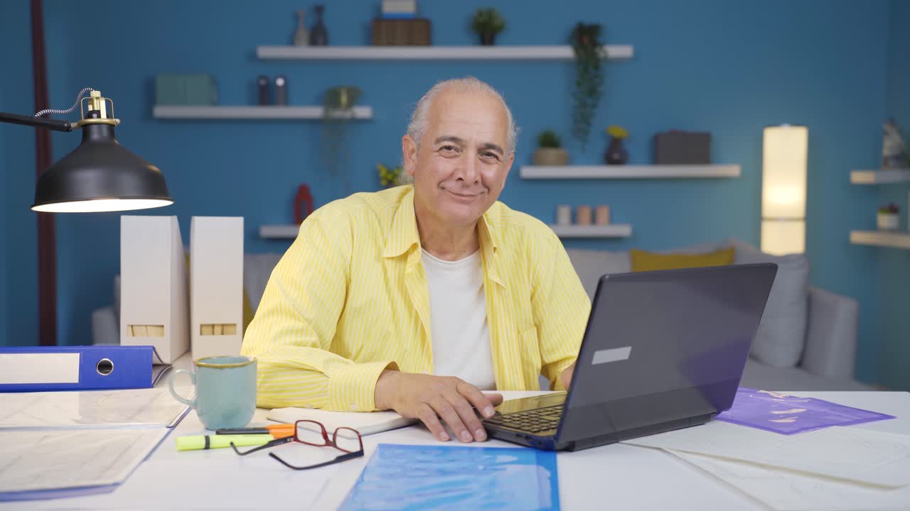 Home office worker old man winks at camera.
