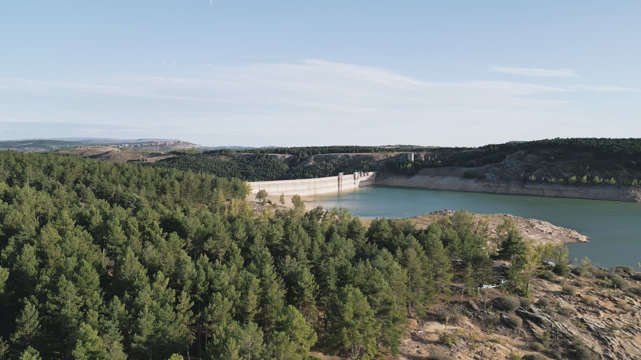 vista aérea de una presa hidroeléctrica rodeada por un embalse y pinos en la orilla