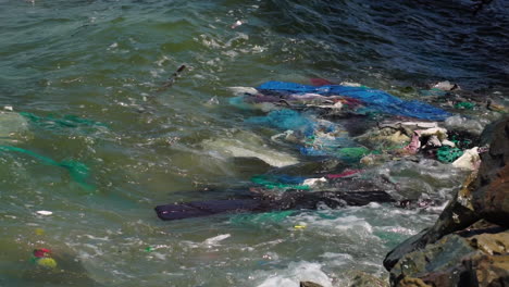 elementos contaminantes evidentes que flotan en el mar cerca de las rocas