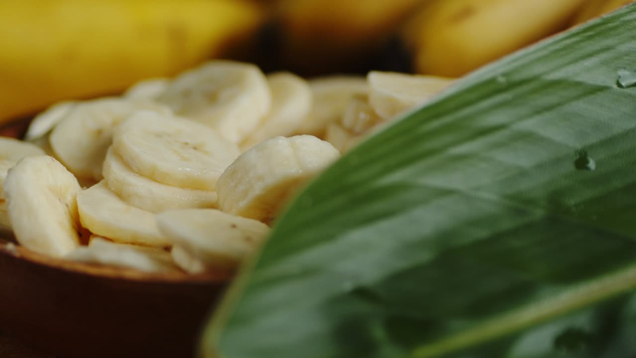 Slices of fresh banana on a wooden plate slowly rotate.