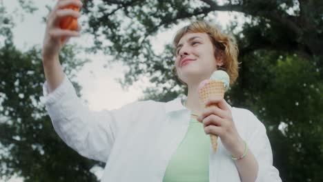 woman taking selfie with ice cream in park