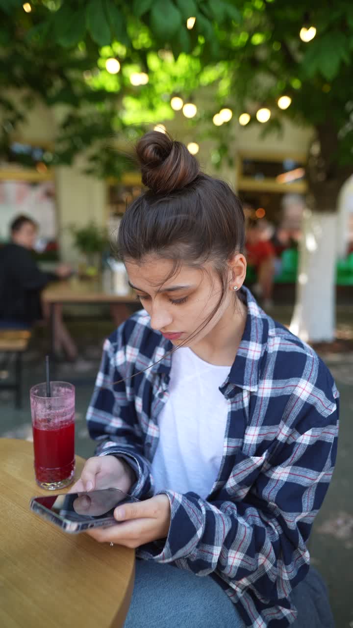 joven usando un teléfono inteligente en un café al aire libre