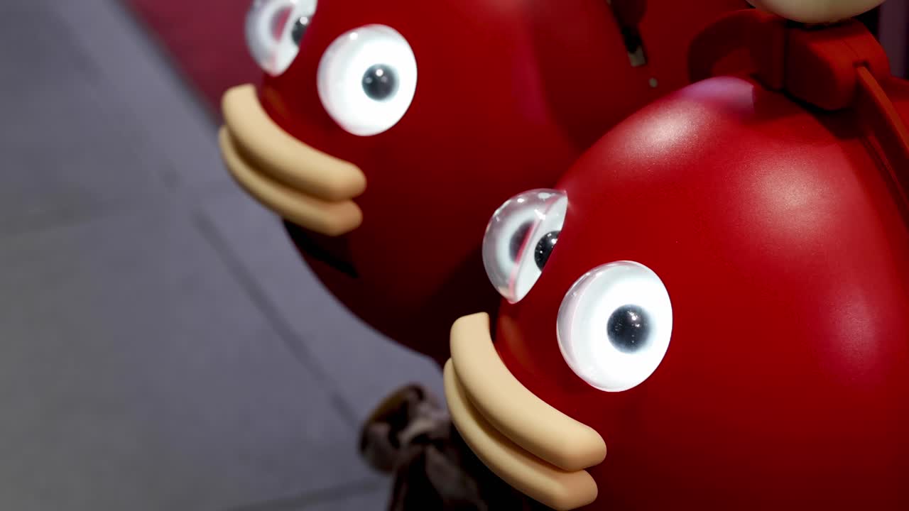 A series of red cartoon faces with large eyes and expressive mouths in a playful arrangement.