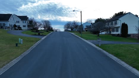 drone flyover asphalt road in hilly american neighborhood at dawn