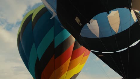 globos de aire caliente completamente inflados al amanecer soplando en el viento con nubes detrás