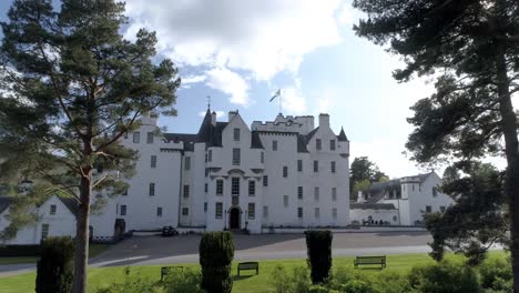 low aerial pull back, parallax shot of blair castle flying the scottish flag of the saltire