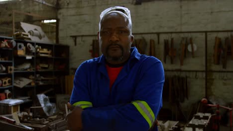 metalsmith standing with arms crossed in workshop 4k