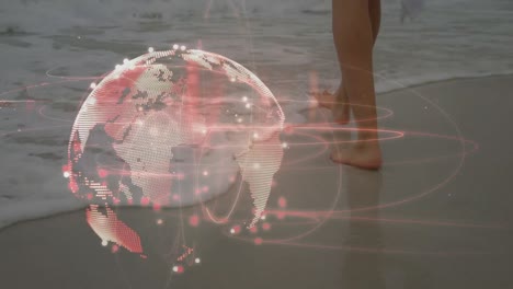 Light-trails-over-spinning-globe-against-low-section-of-a-woman-walking-at-the-beach