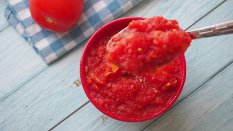 homemade tomato sauce in a red bowl with spoon