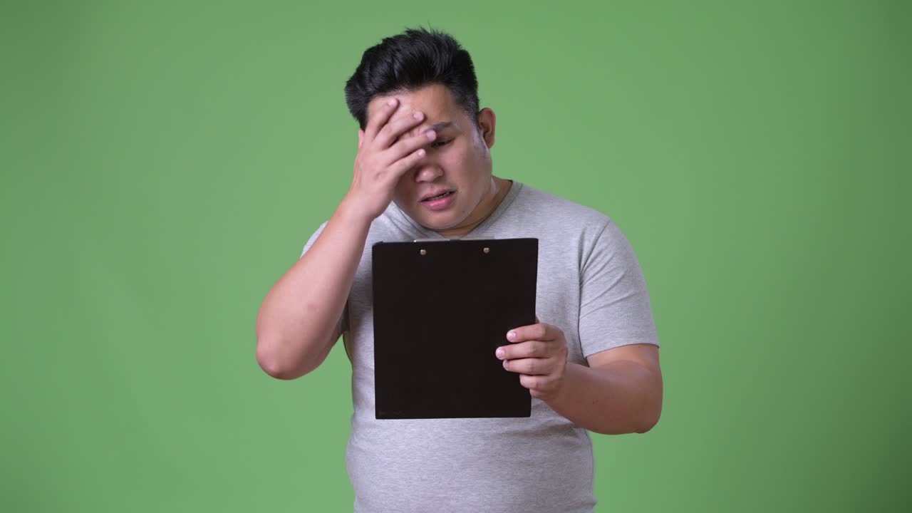 초록색 배경에 젊은 잘생긴 과체중 아시아인