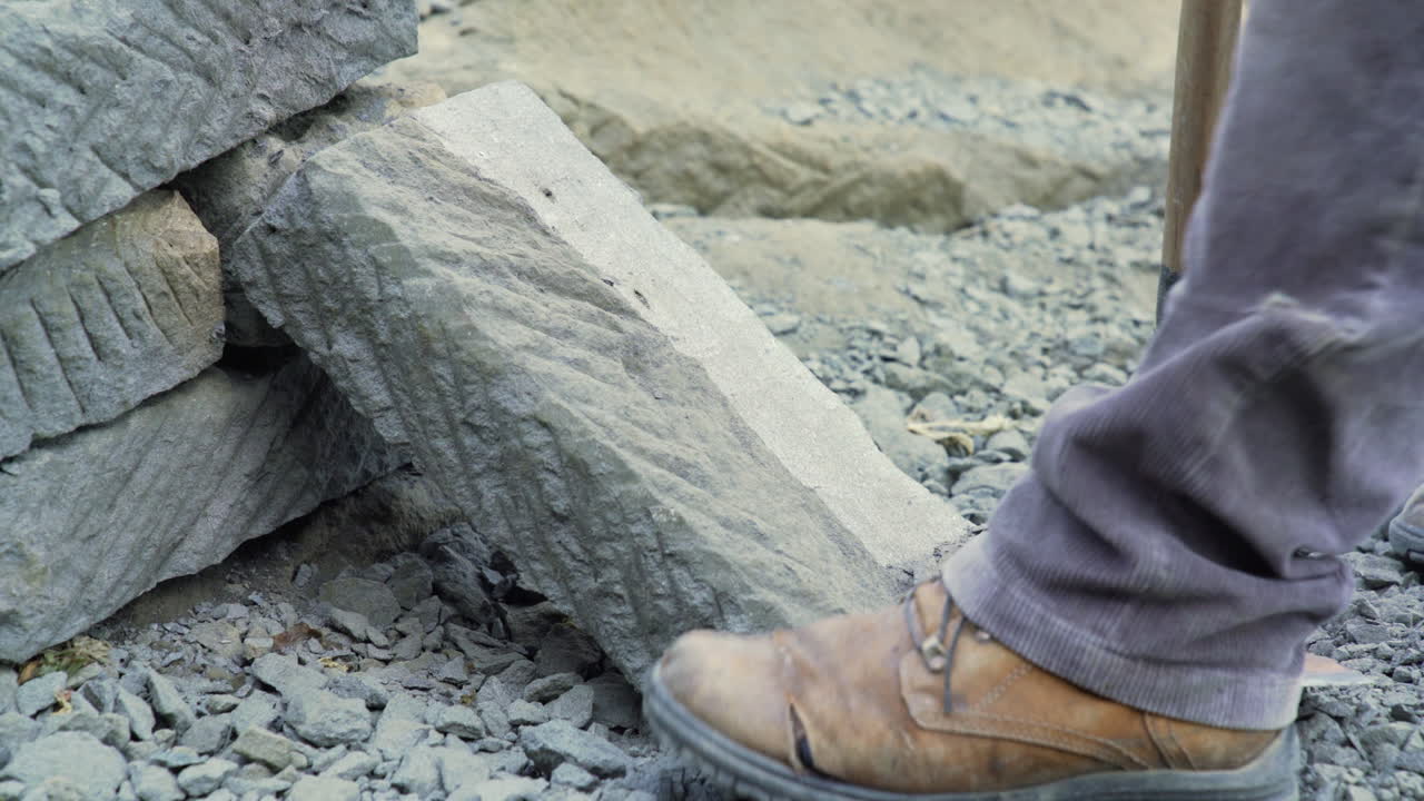 Handheld shot of someone edging a large square slab of cancagua stone with a handheld pick in the city of Ancud, Chiloe Island.