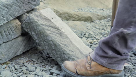 handheld shot of someone edging a large square slab of cancagua stone with a handheld pick in the city of ancud, chiloe island.