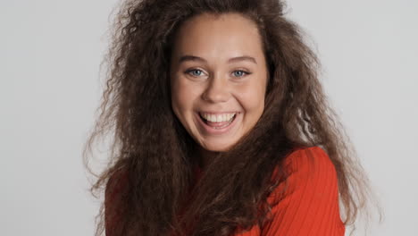 caucasian curly haired woman sending a kiss to camara.