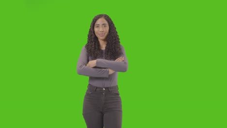 three quarter length studio portrait of woman against green screen smiling at camera 1