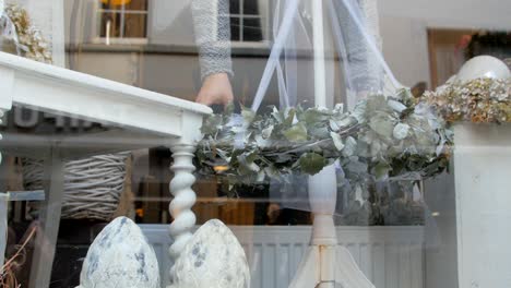 a woman decorates her shop window for the christmas season