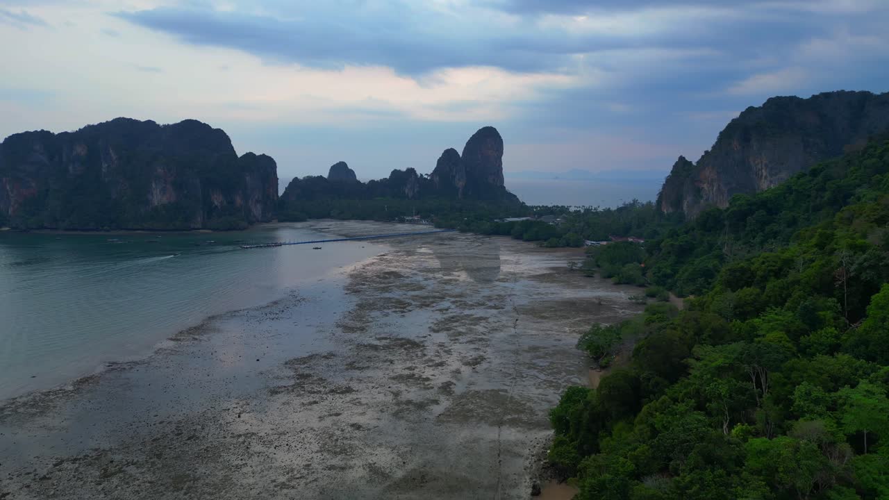Limestone karst formations at low tide, Railay Beach Krabi, Thailand. Breathtaking aerial view flight fly reverse drone