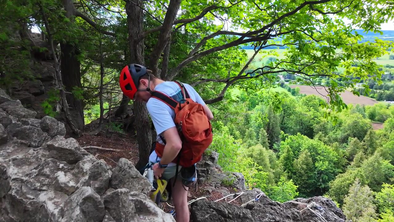 Scalatore di roccia che si cala in corda doppia dal bordo di una scogliera presso l'Area di Conservazione di Rattlesnake Point in Ontario, Canada.