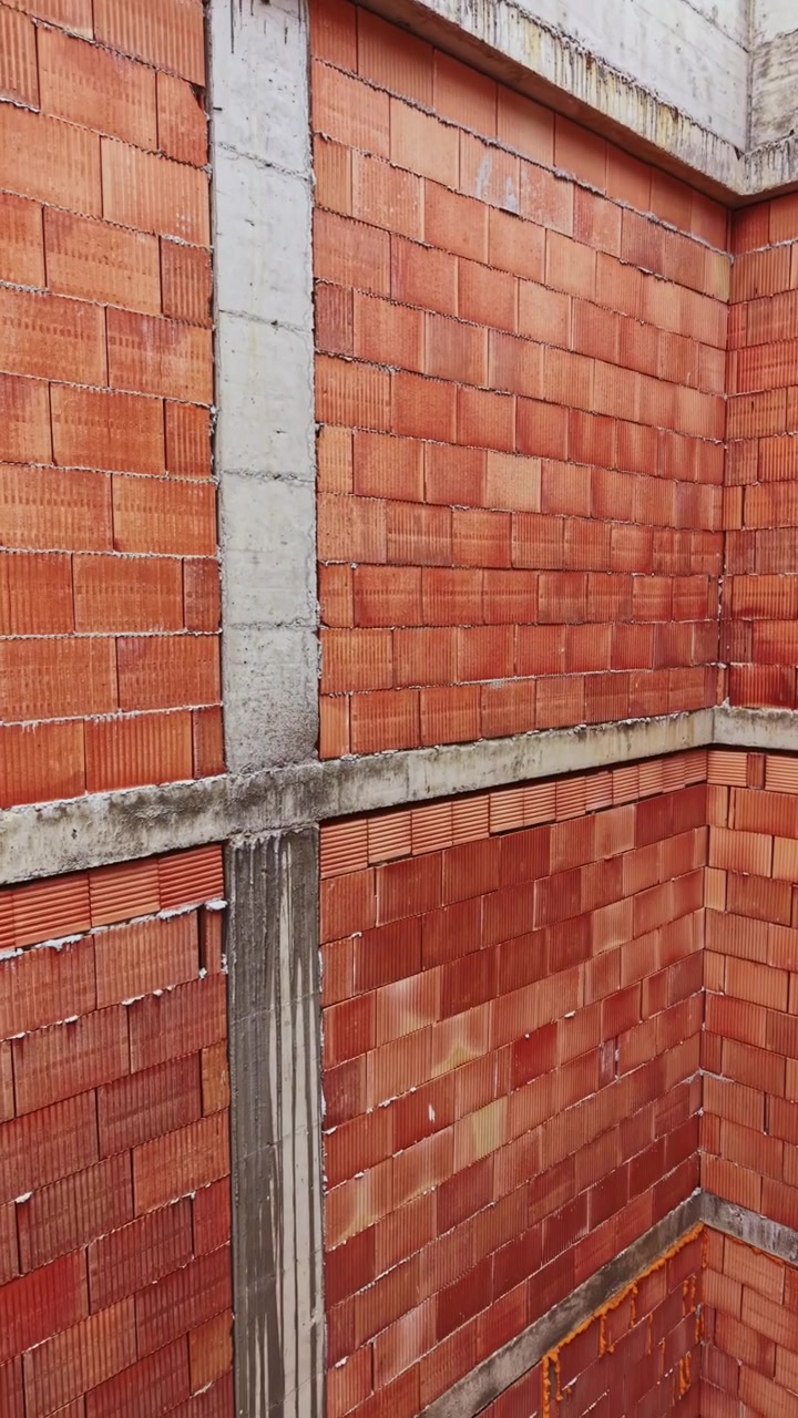 Construction progress of a multi-storey building made of brick and concrete in an urban area during daylight hours