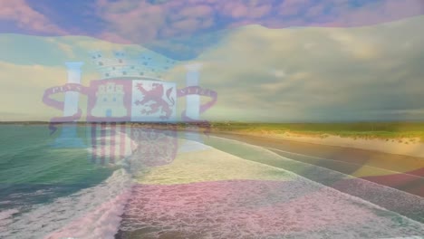 animación de la bandera de españa ondeando sobre el paisaje de la playa, el mar y el cielo azul nublado