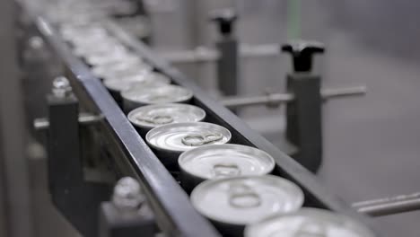 closeup of cans moving on a conveyor belt in a food production line, featuring automation, packaging, sealing, quality control in an industrial setting