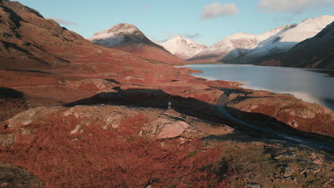 acercándose a excursionista en la ladera al atardecer con montañas cubiertas de nieve y el lago en wasdale lake district uk