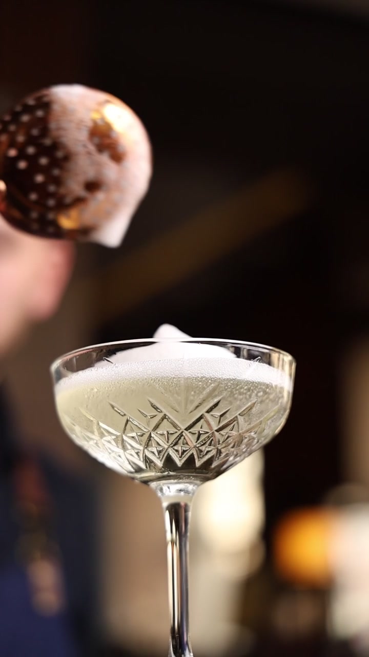 Barman che aggiunge schiuma a un bicchiere da cocktail di cristallo