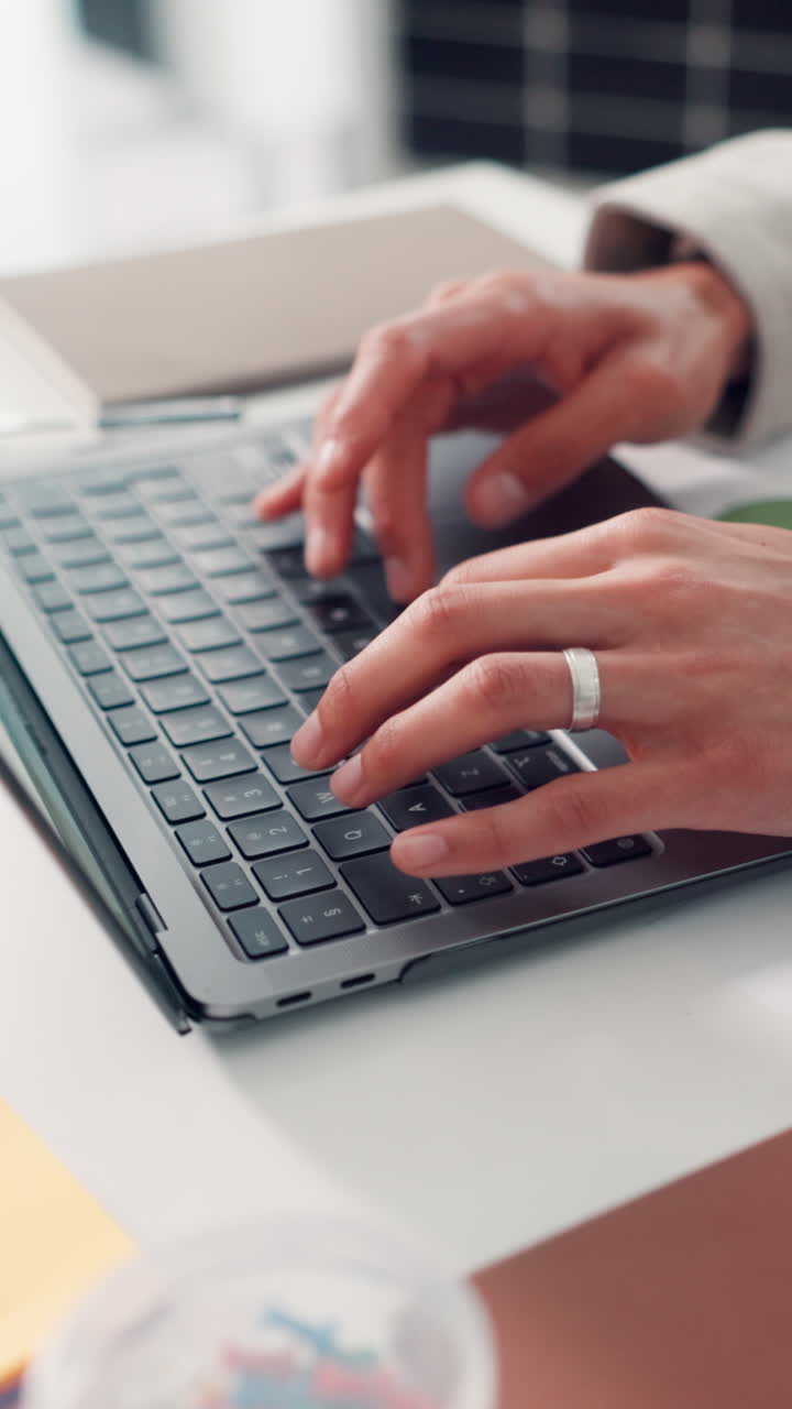 Primo piano di mani che digitano sulla tastiera di un laptop a una scrivania.