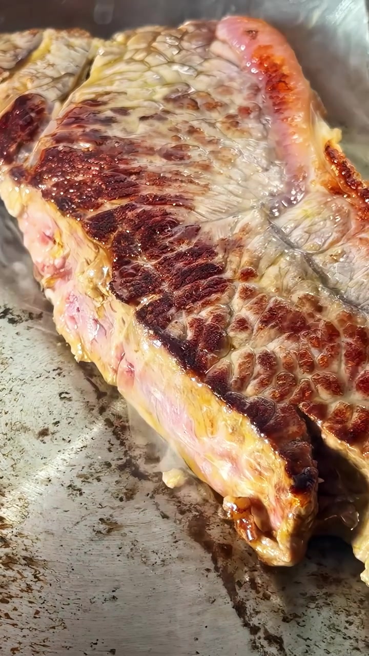 Una succosa bistecca di manzo sfrigola su una griglia calda, mostrando una crosta perfetta e un interno tenero. Ideale per contenuti culinari o tutorial di cucina.