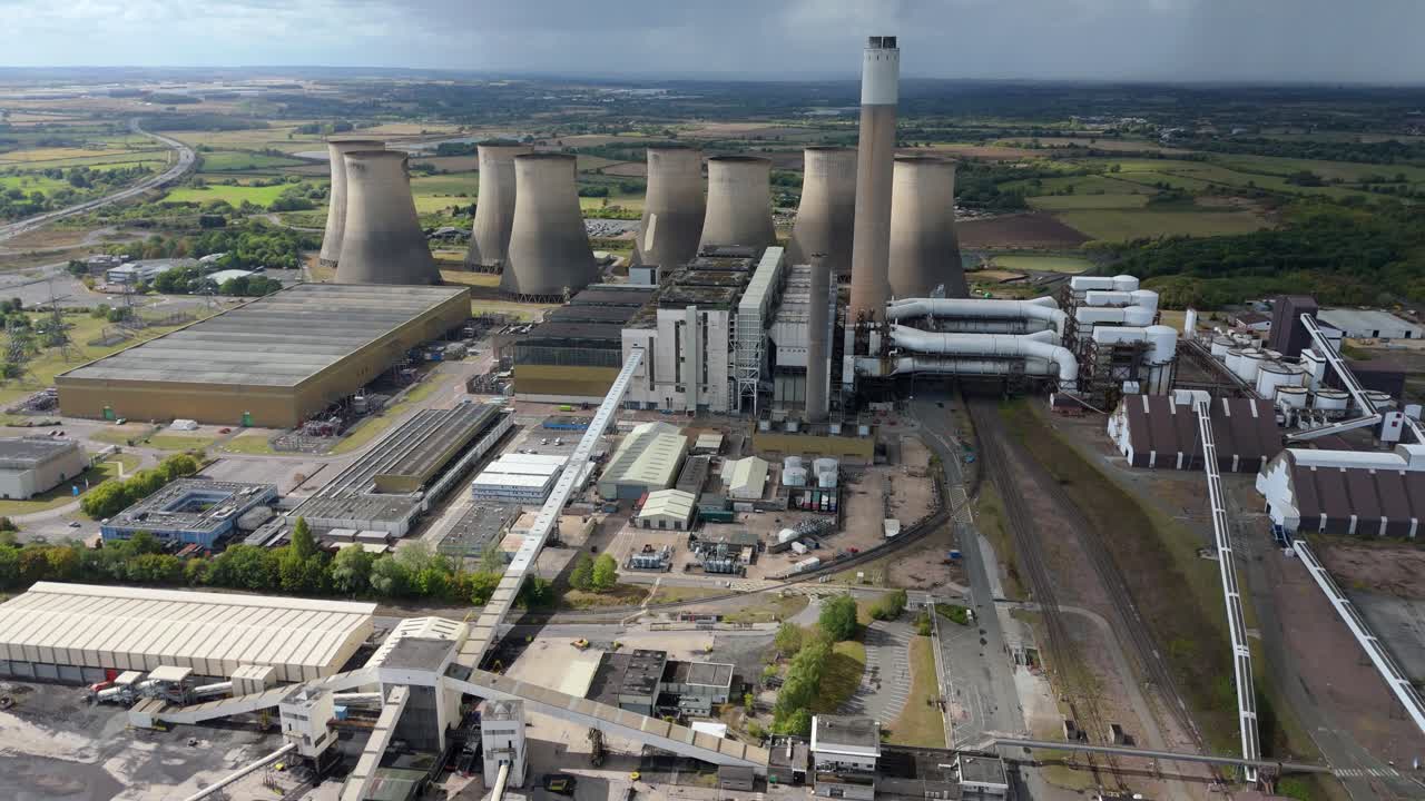 - High altitude drone view of coal power facility with cooling towers and turbulent skies in central England