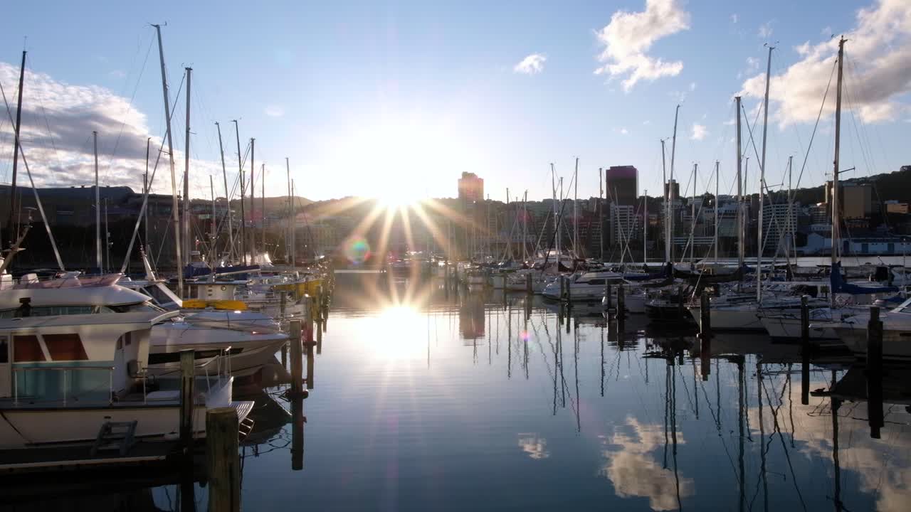yates y barcos atracados en el puerto deportivo frente al mar de la ciudad, hermosa tarde soleada, rayos de sol, reflejos, cielos azules y paisaje urbano de wellington, nueva zelanda