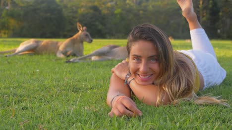 Beautiful-Girl-Lying-And-Relaxing-On-The-Green-Grass---Eastern-Grey-Kangaroos-Resting-Under-The-Shade-Of-Trees---Gold-Coast,-QLD,-Australia