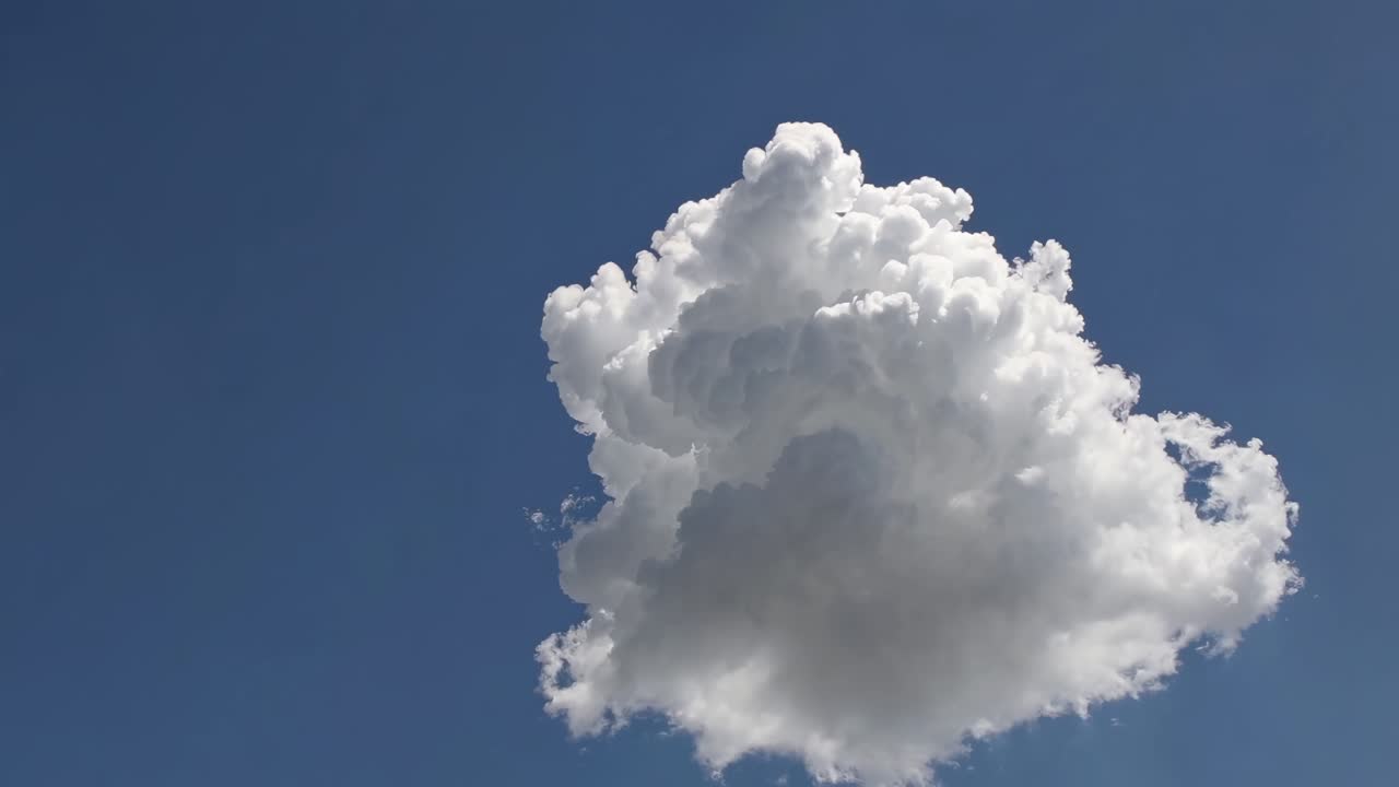 A low-angle video captures a single fluffy cloud against a clear blue sky, emphasizing tranquility