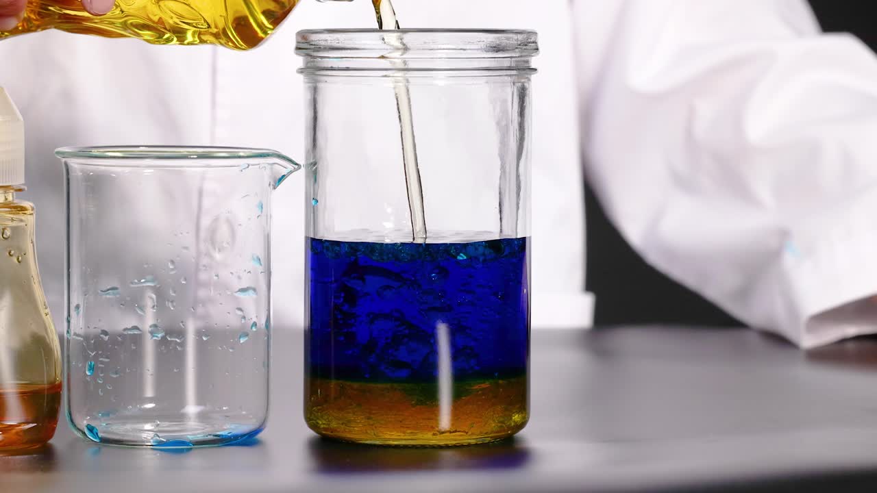 un experimento de líquido vibrante se desarrolla en un frasco de vidrio, mostrando cambios dinámicos de color e interacciones en un entorno de laboratorio