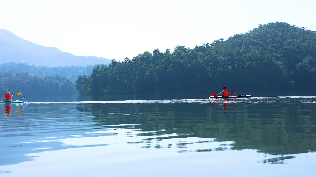 Two kayakers paddle peacefully on a calm lake