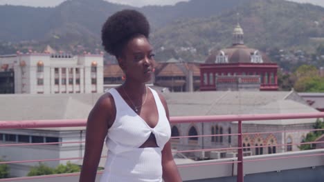 una chica negra en un vestido blanco domina la ciudad mientras camina en un techo