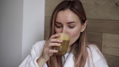 mujer joven bebiendo jugo de manzana fresco en la cocina por la mañana