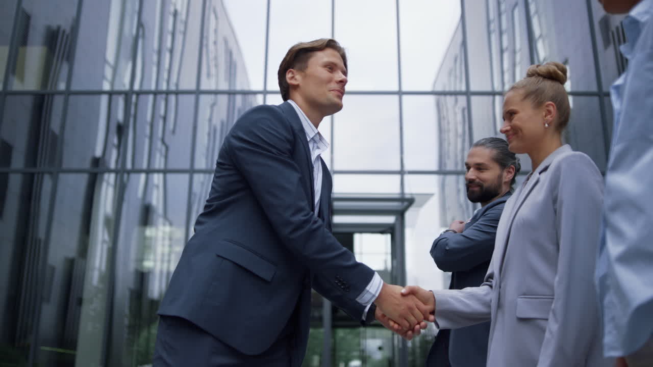 благодарный лидер пожимает руки, приветствуя улыбающихся членов команды в офисном здании.