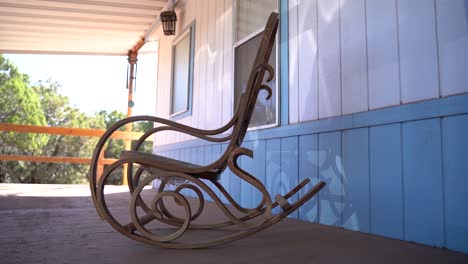 Grandma's-Old-Wooden-Rocking-Chair-on-Porch-of-Secluded-Forest-Cabin-in-Slow-Motion