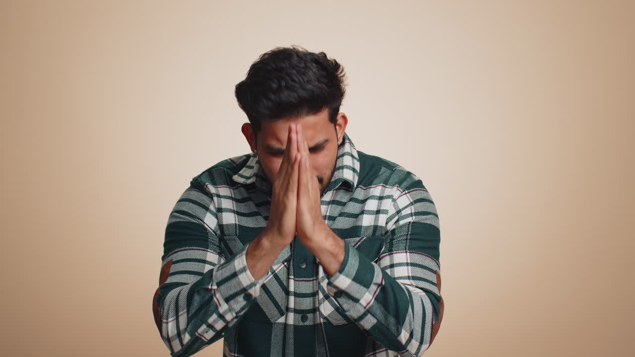 Indian handsome man praying looking upward making wish begging apology asking help forgive me
